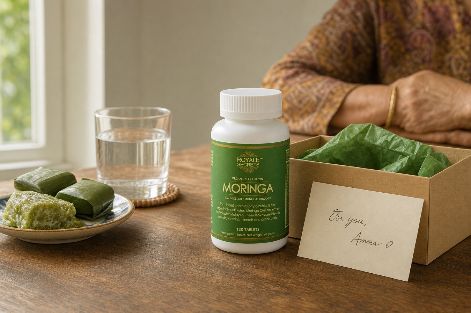 Botol Royale Secrets Moringa di atas meja dapur, bersama kotak hadiah dan kad nota